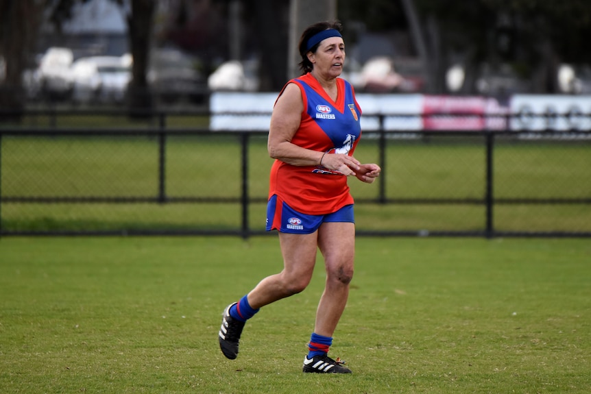 Aussie Rules masters player Michelle Lewis runs towards the boundary during a game.