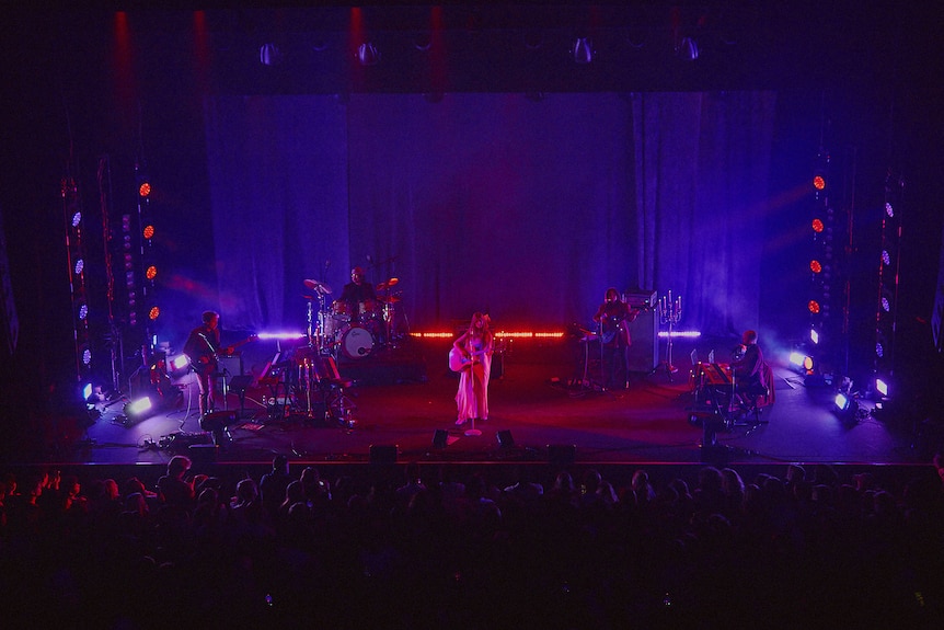 A wide shot of Weyes Blood and her four-piece band performing live on stage at Melbourne's Forum