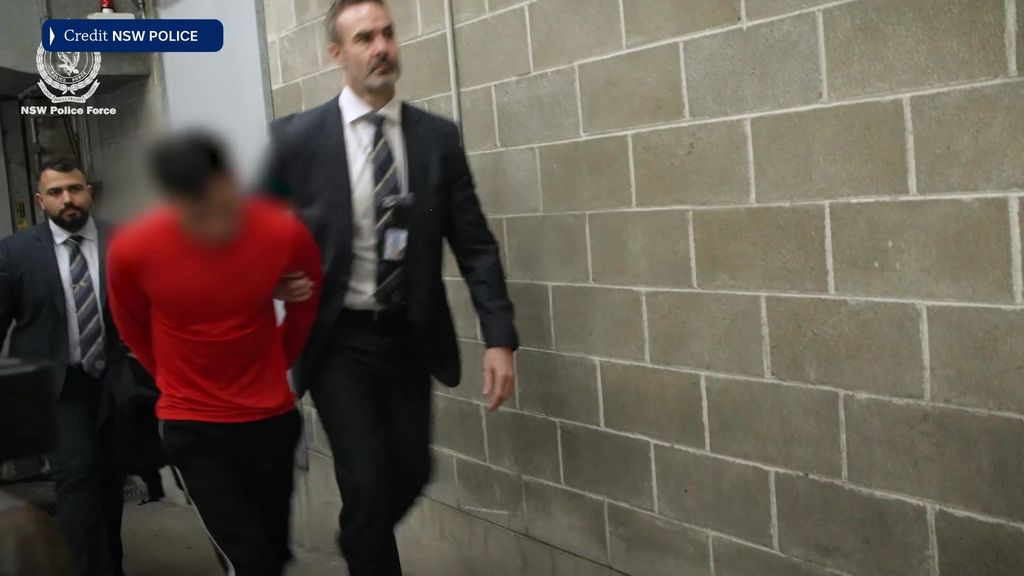 Man in red escorted by NSW Police