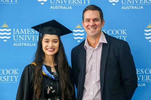 Daniel Christie standing with a female student who wears a graduating gown