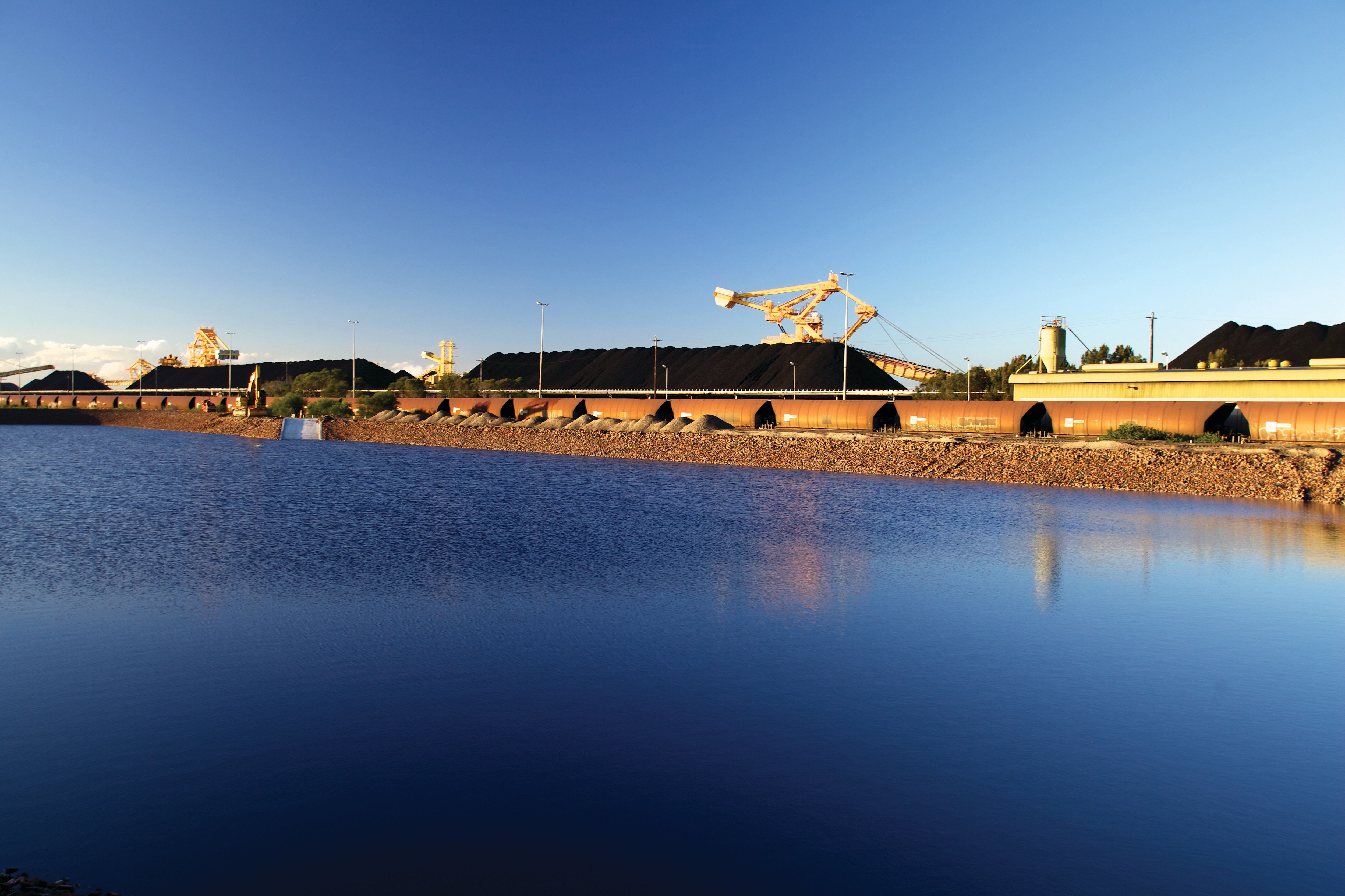 Coal train wagons next to ocean.