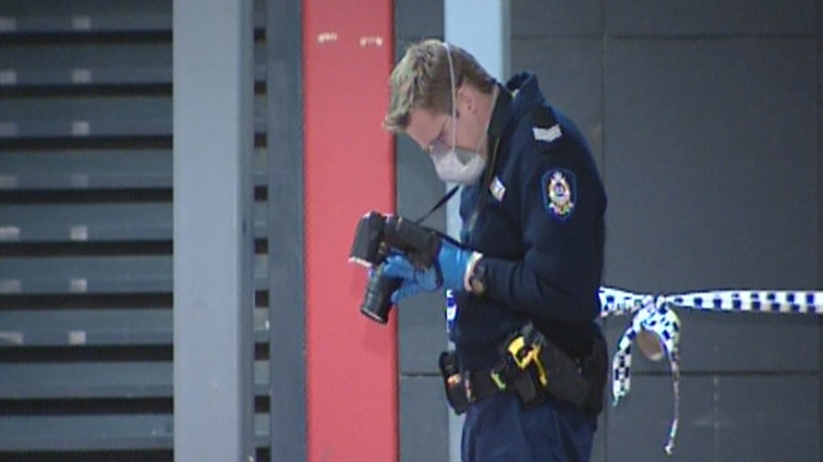 A police forensics officer photographs a scene in Armadale where a man was stabbed in the back on Jull Street.