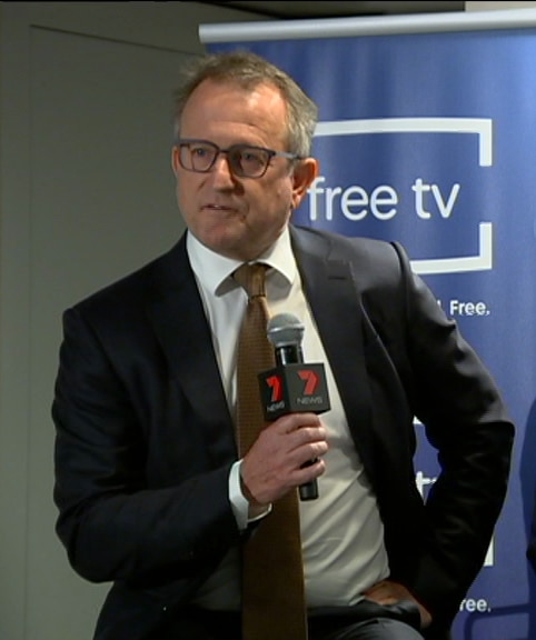 Image of Craig McPherson holding a 7 News microphone.
