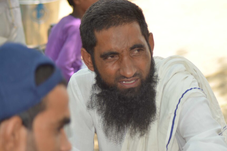 A closeup of a Muslim man in India sitting with another person.