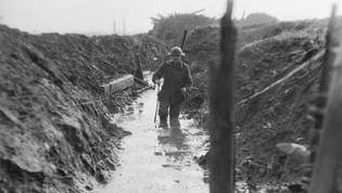 A soldier makes his way through a trench along the Western Front during WW1.