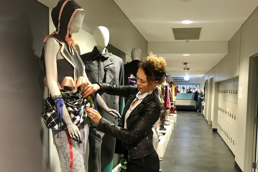 A woman pins fabric to a mannequin.
