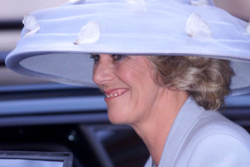 Camilla Parker Bowles in a powder-lilac jacket and stunning matching hat, smiles as she opens a car door