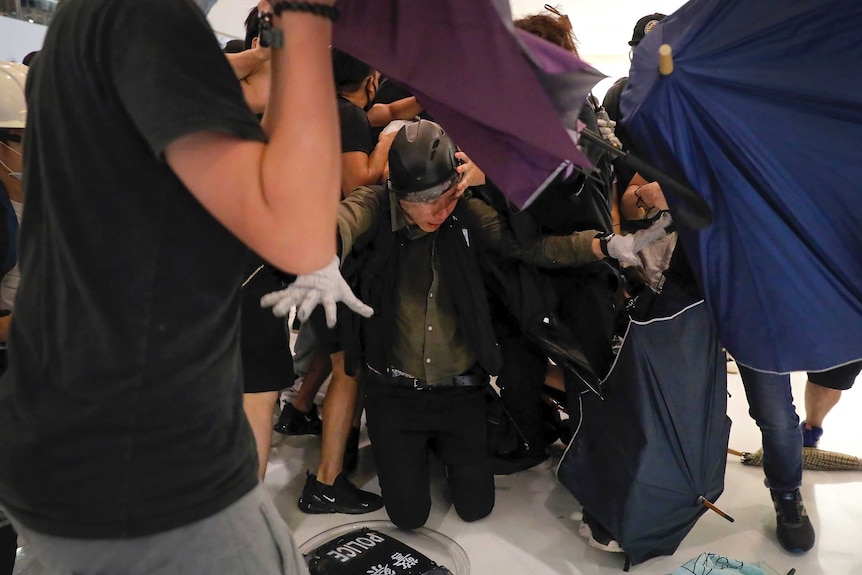 A policeman kneels on the floor as he attacked by protesters.