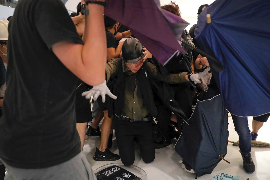 A policeman kneels on the floor as he attacked by protesters.