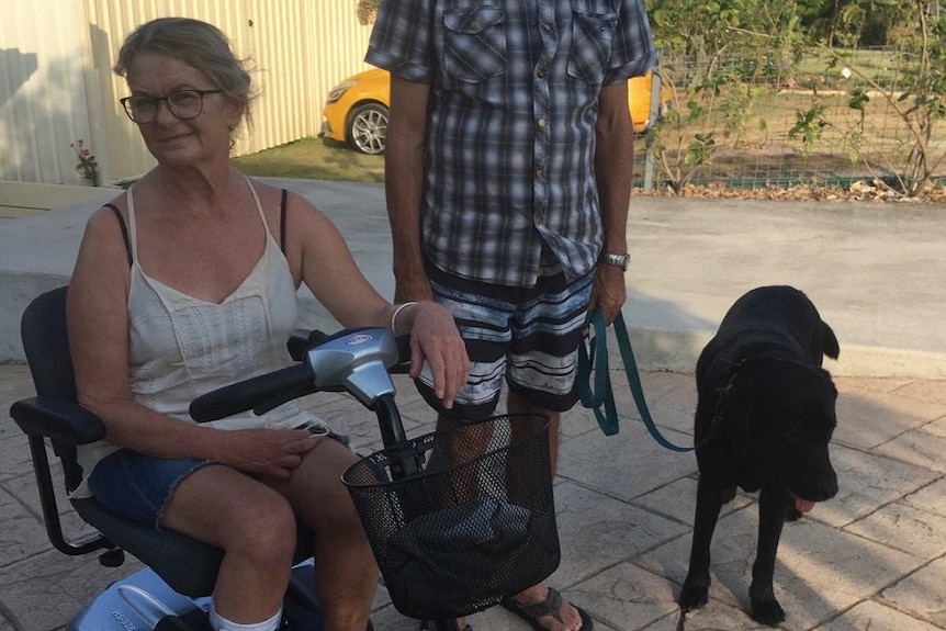 A woman on a mobility scooter with her father and black dog on a lead