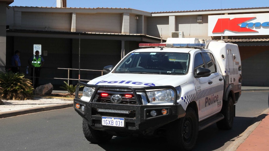A police car outside a shopping centre with a Kmart sign in the background.