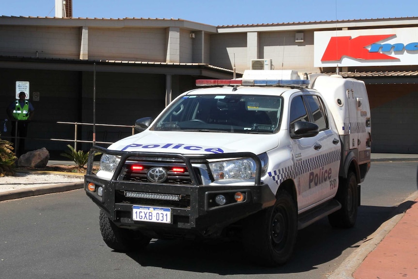 A police car outside a shopping centre with a Kmart sign in the background.