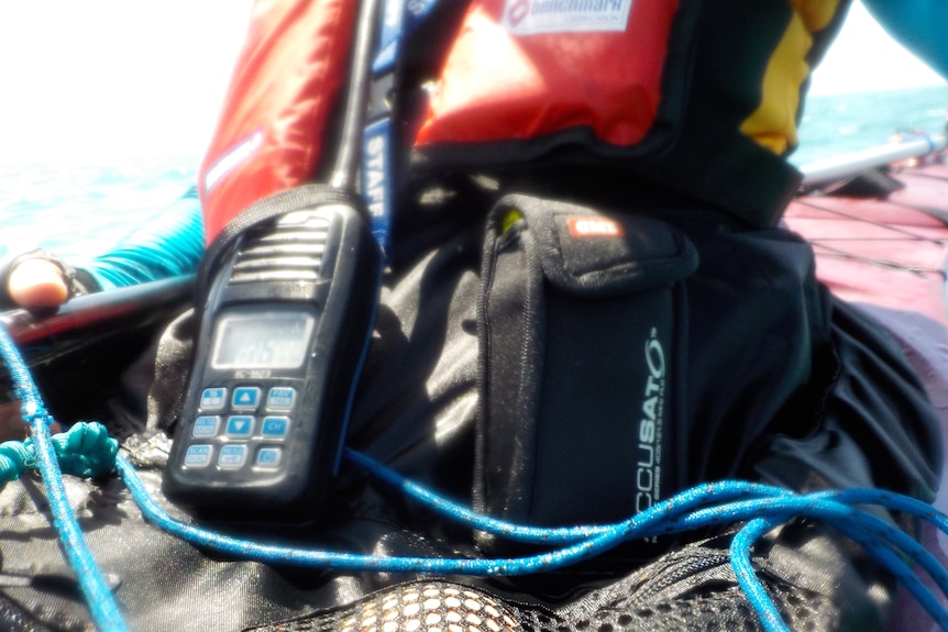 A marine VHF radio and locator device are fit tightly around Lyn's waist