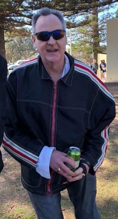 A man wearing a black jacket with red and white striped detail.