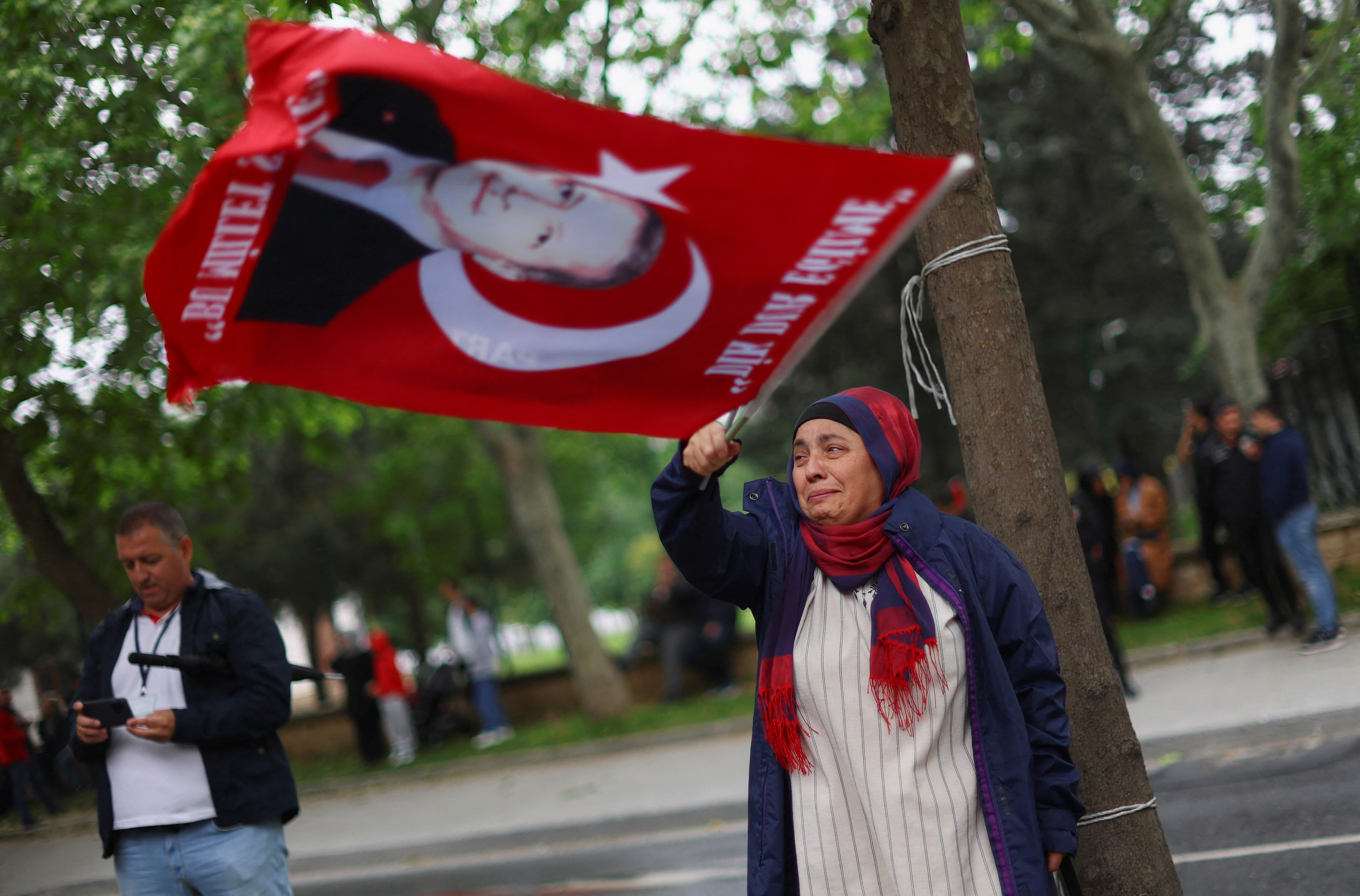 A woman cries waving a flag showing Turkish President Tayyip Erdogan's face.