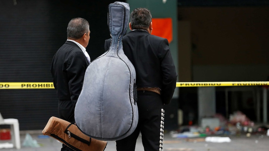 Mariachi musicians observe shooting scene