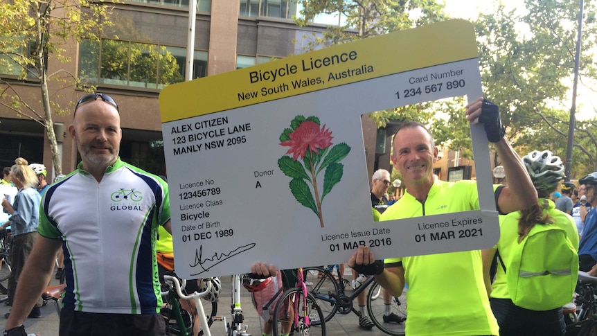 Cyclists protesting against new cycling laws hold a giant licence card near NSW Parliament House.
