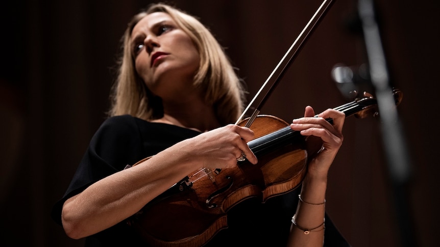 Satu Vänska stares into the distance while holding her Stradivarius violin sideways.