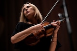 Satu Vänska stares into the distance while holding her Stradivarius violin sideways.