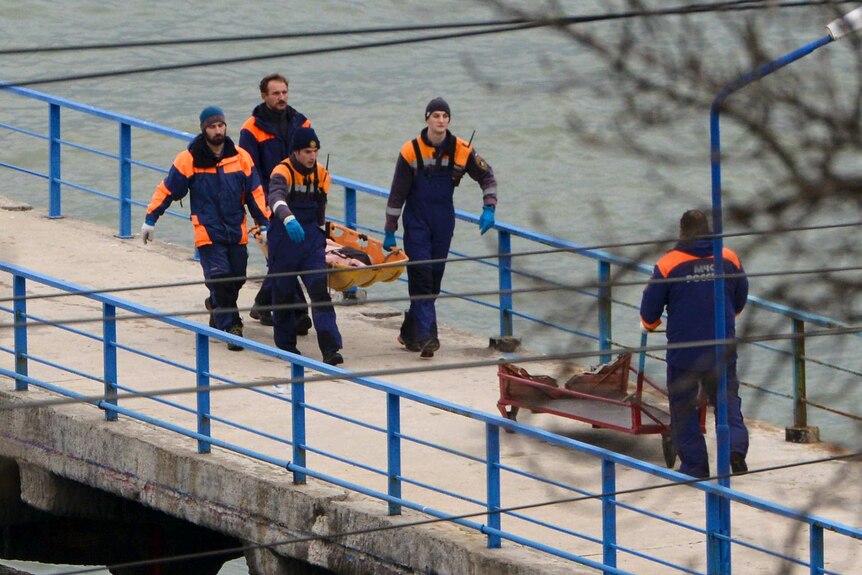 Rescue workers carry body from wreckage of plane crash