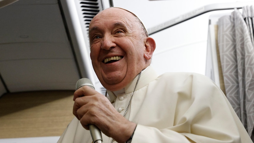 Pope Francis smiling holding a microphone