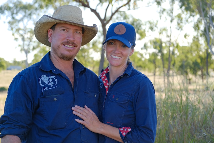 Kale and Karin Robinson smiling at the camera in royal blue work shirts.