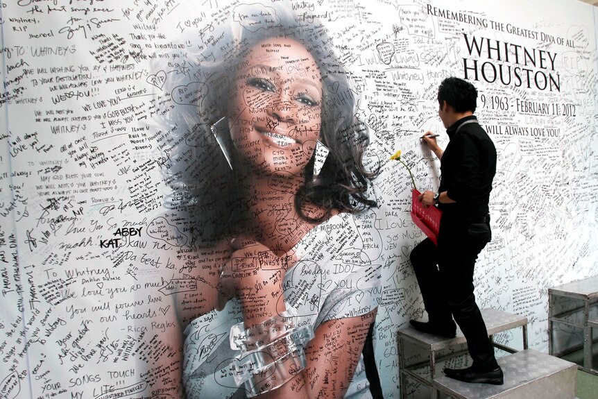 A Filipino fan writes a message on a tribute wall for Whitney Houston.