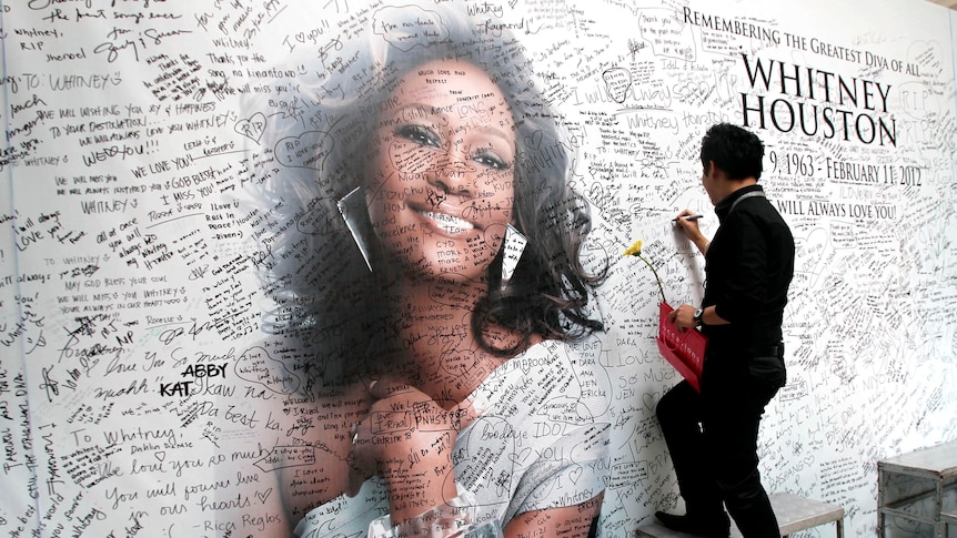 A Filipino fan writes a message on a tribute wall for Whitney Houston.