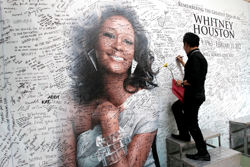 A Filipino fan writes a message on a tribute wall for Whitney Houston.