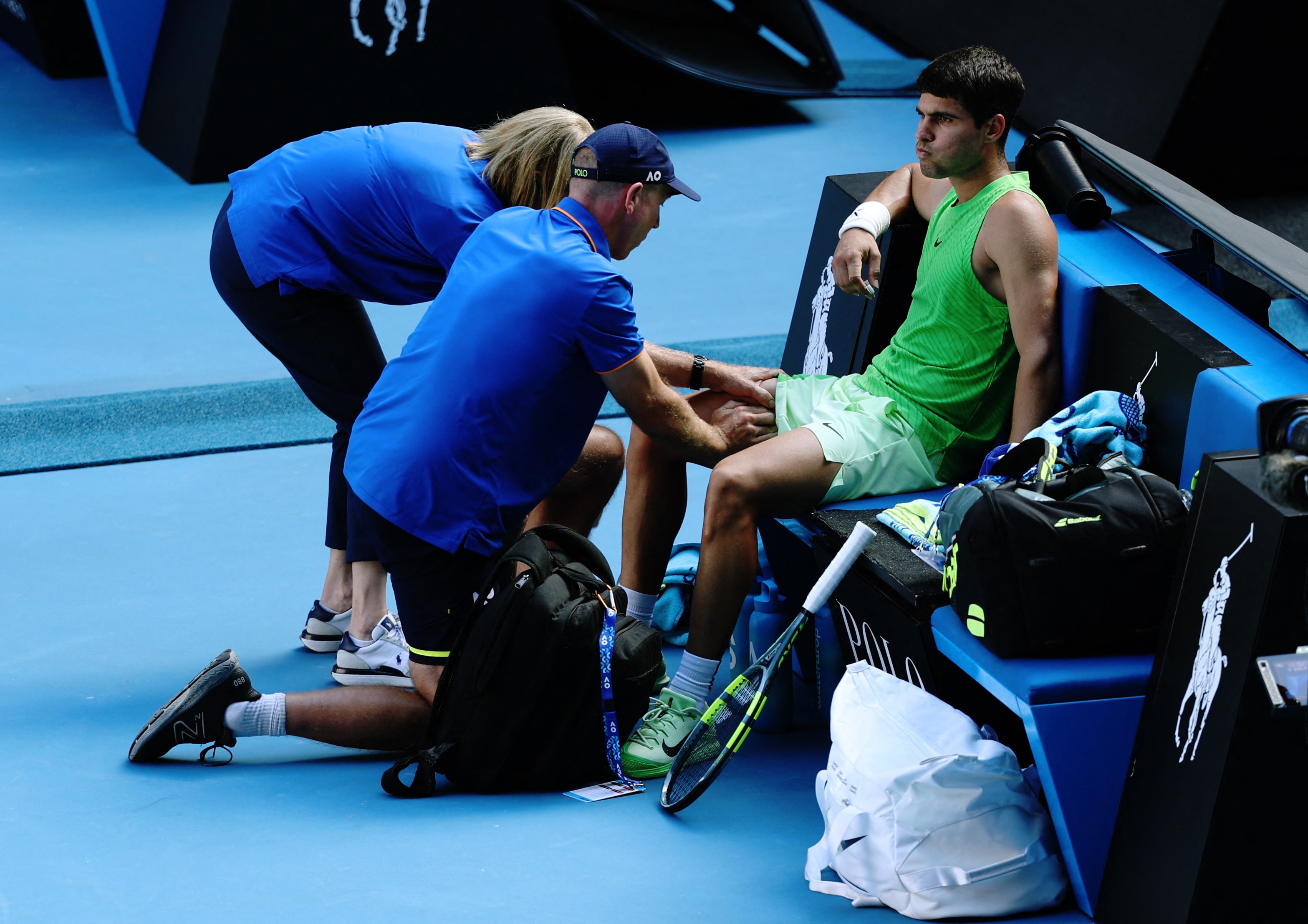 Carlos Alcaraz gets his leg massaged by a physiotherapist on the pitch