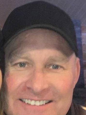 Headshot of a smiling man wearing a cap