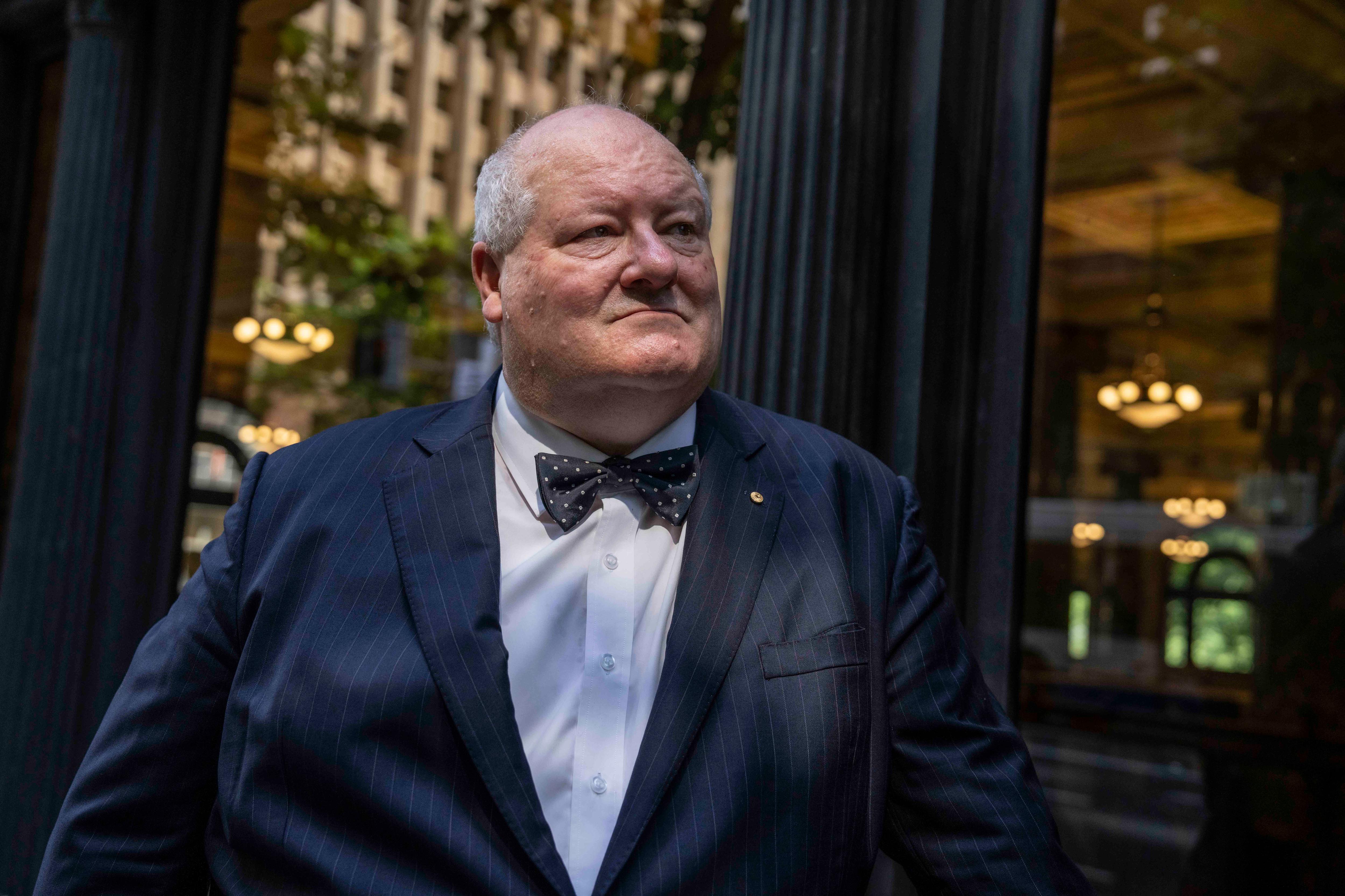 a man in a bowtie stands outside a window