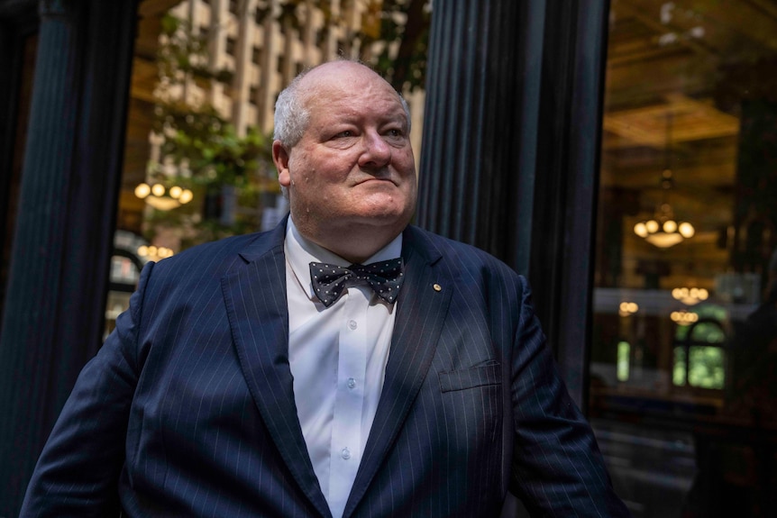 a man in a bowtie stands outside a window