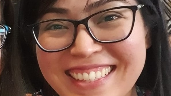 A woman wearing glasses smiles.