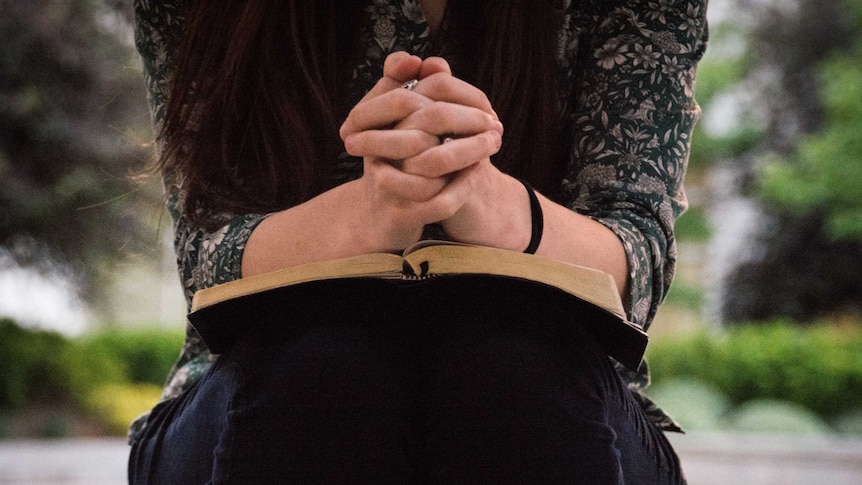 A woman prays over a bible