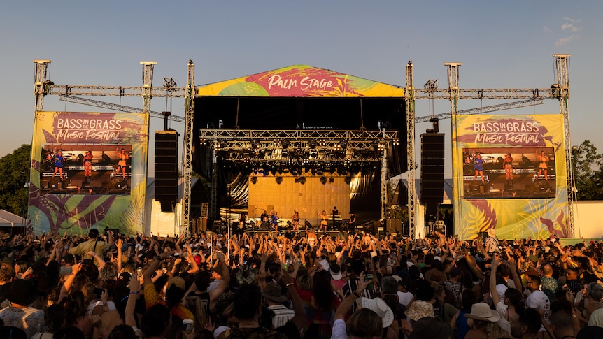 A packed festival crowd in early evening sunlight watches the massive Palm Stage at NT's BASSINTHEGRASS festival 2022
