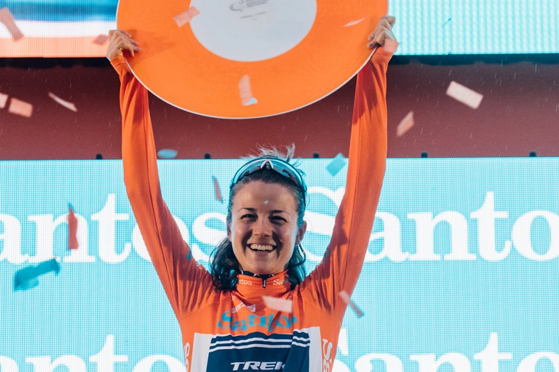 Cyclist Ruth Winder holds a trophy plate above her head on the podium after winning the Santos Tour Down Under in Adelaide.