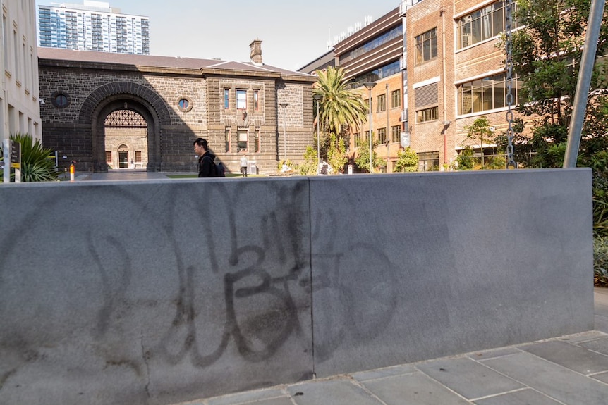 A black graffiti tag is visible on the back of the concrete memorial.