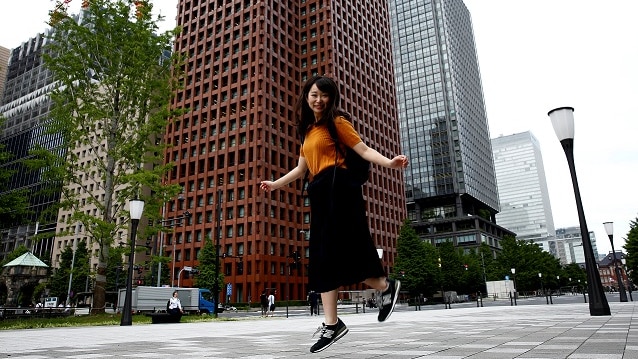 Yumi Ishikawa jumps as she poses at a business district during an interview with Reuters in Tokyo.