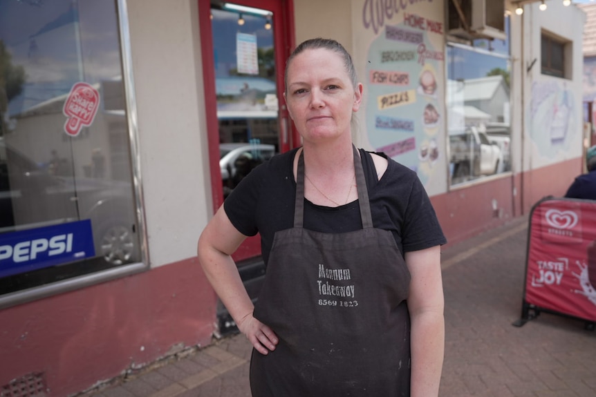 A woman with very short hair wearing an apron in a shop