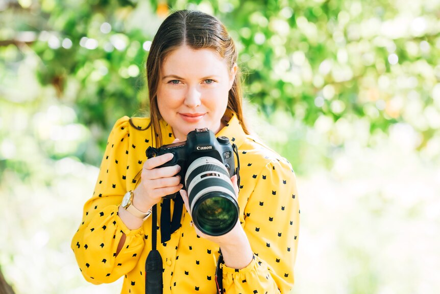 Woman holding camera poses for photographer