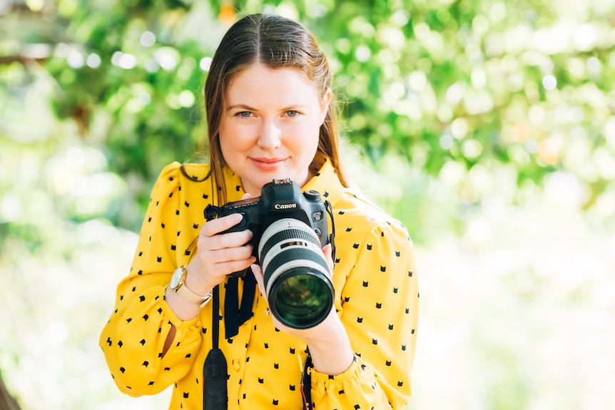 Woman holding camera poses for photographer