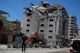 A man walks in front of a building that has suffered damage