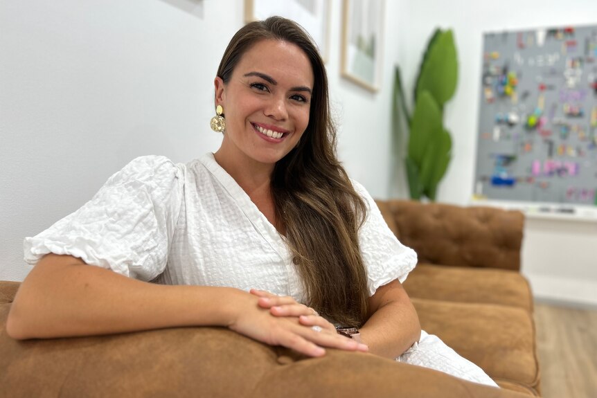 Woman in white smiling on couch
