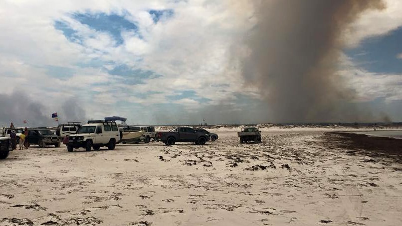 Cars on the beach at Wedge Point, while the bushfire blazes around Wedge Island, north of Lancelin in WA