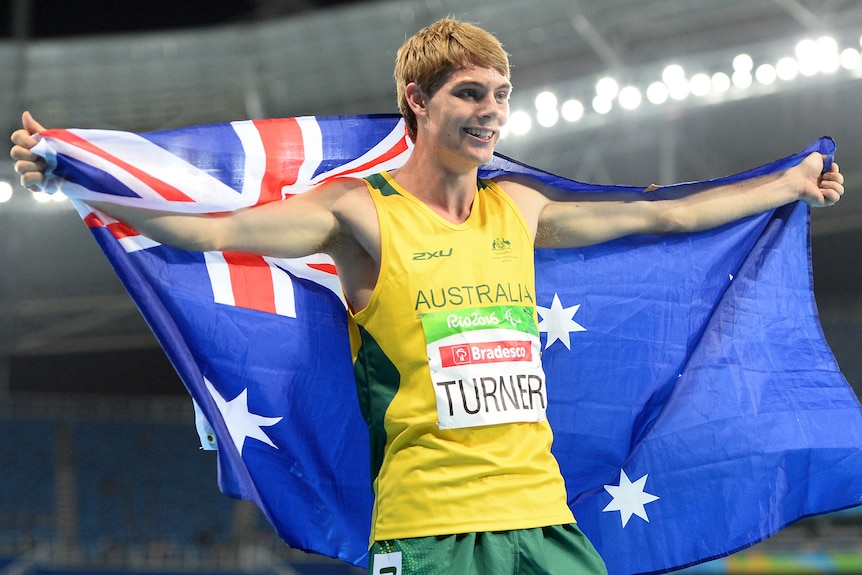 Young man holding the Australian flag behind him smiling