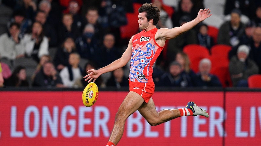 A Sydney Swans AFL player kicks the ball.