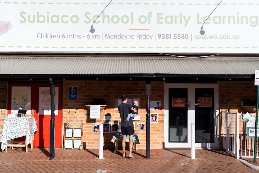 A man holds a child outside the Subiaco School of Early Learning centre in Perth