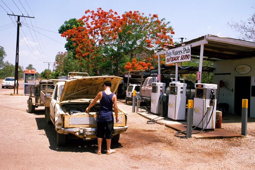 A ute parked outside a small shed with a sign reading "outback servo"