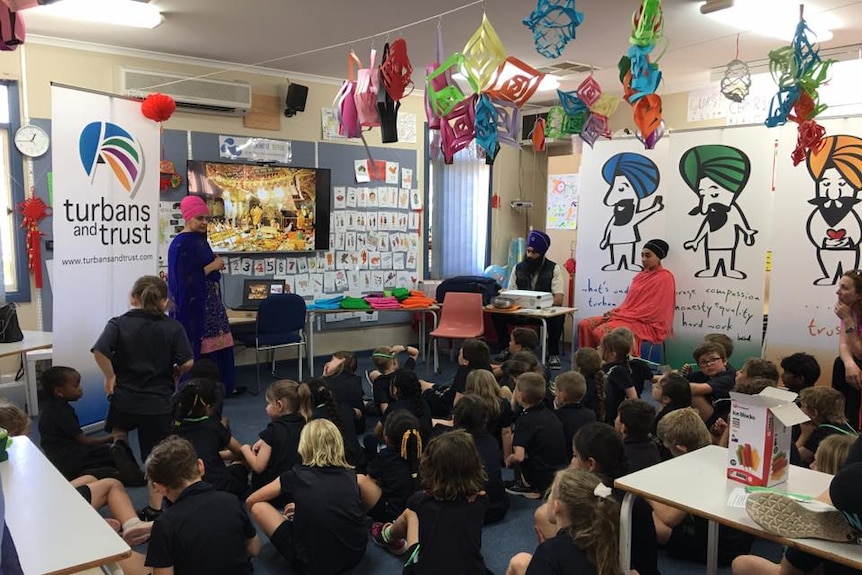 Turban and Trust program coordinators talking to school students in a classroom.